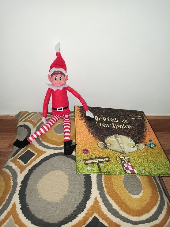 El elfo de Navidad disfrutando de la lectura del libro "Orejas de mariposa".