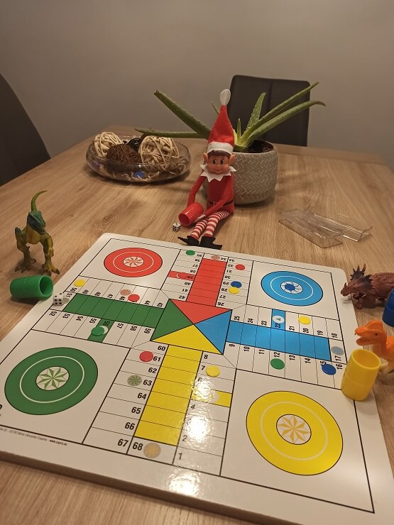 Klaus echando una partida de parchís con sus nuevos amigos, los dinosaurios.